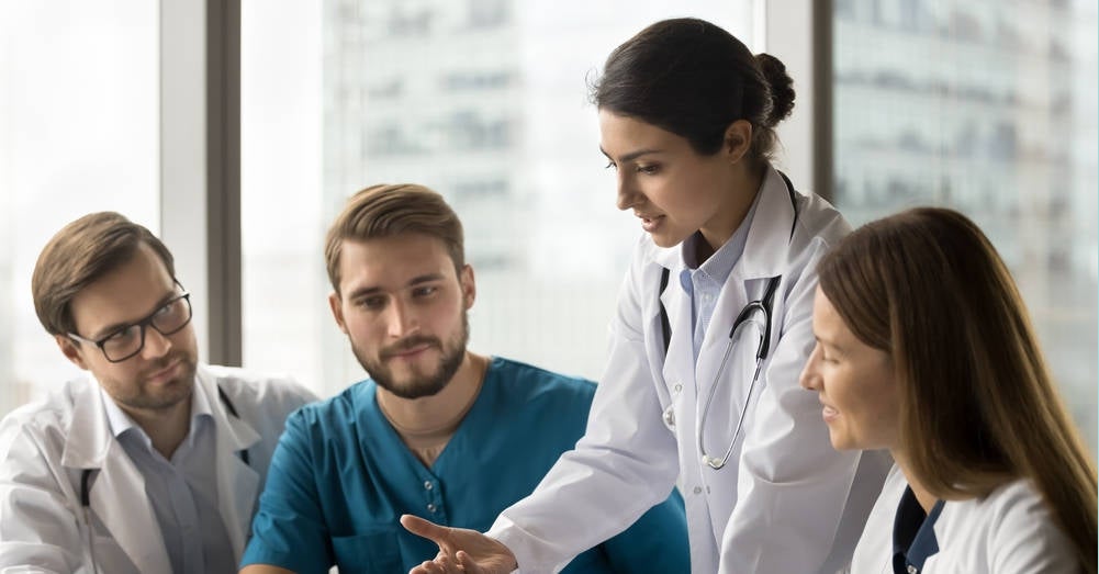 A nurse practitioner going over patient notes with nursing students doing their hospital clinical placement.